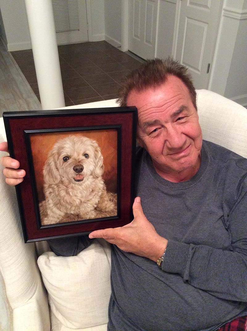 Man holding framed painting of a fluffy dog.