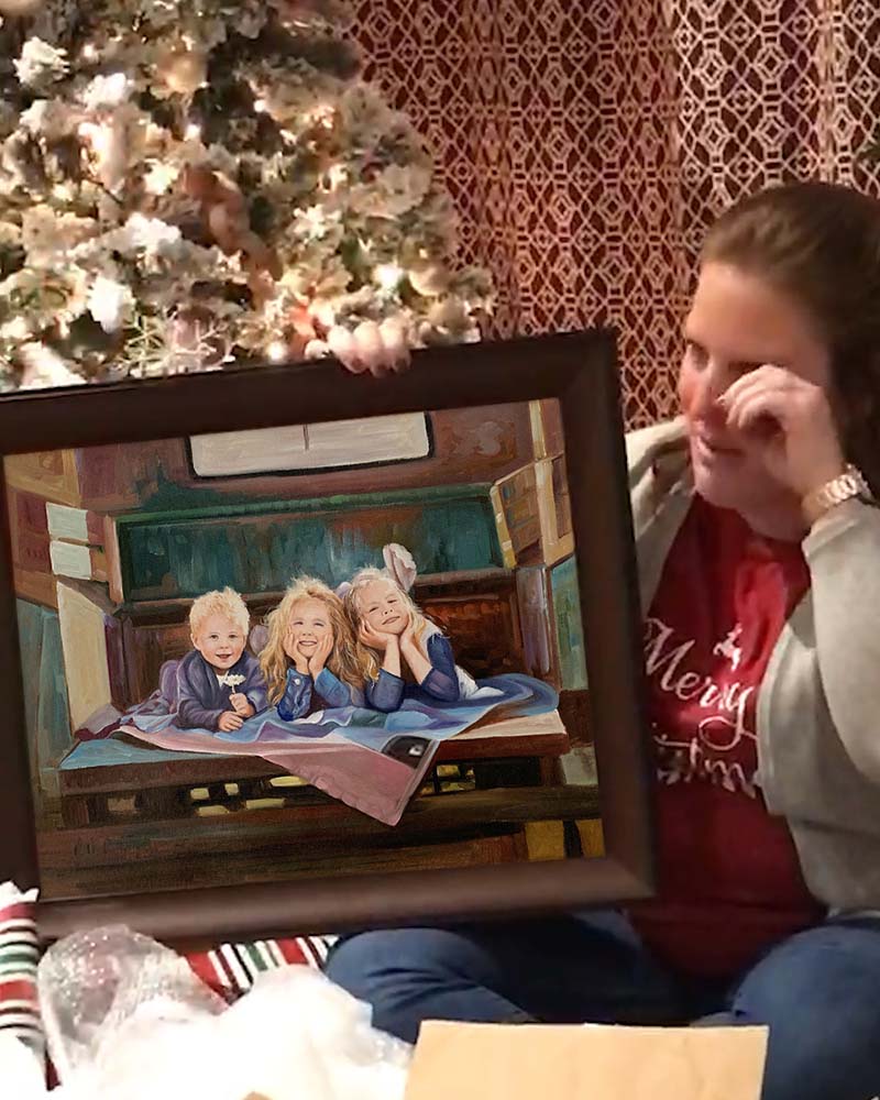 Woman crying happily while holding a framed portrait of three young children near a Christmas tree.