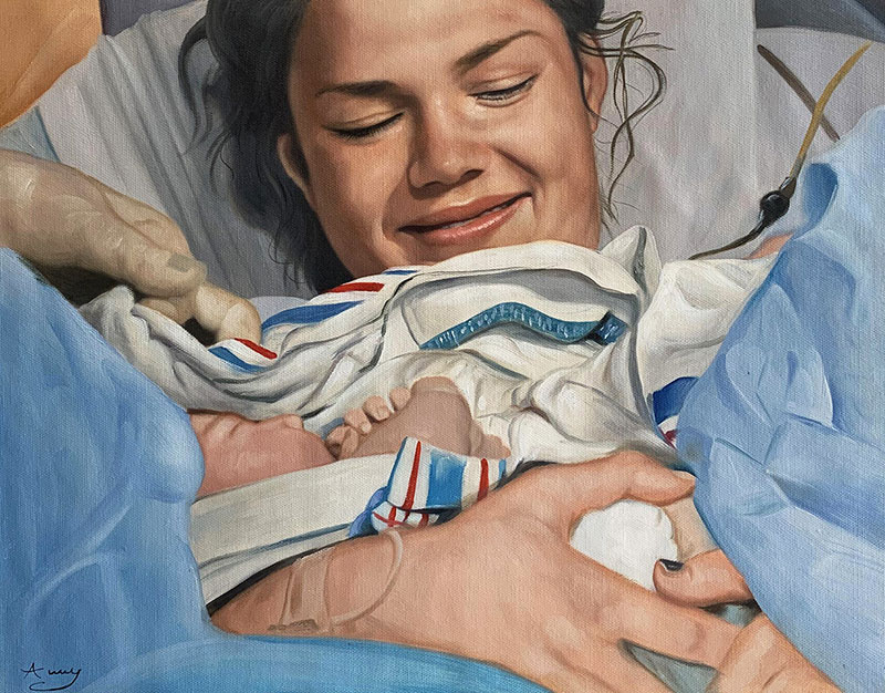 Smiling mother holding newborn baby in hospital bed.