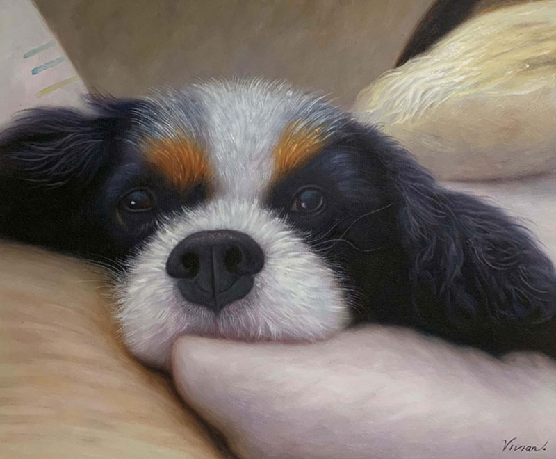 Painting of a Cavalier King Charles Spaniel resting its head on a person`s arm.