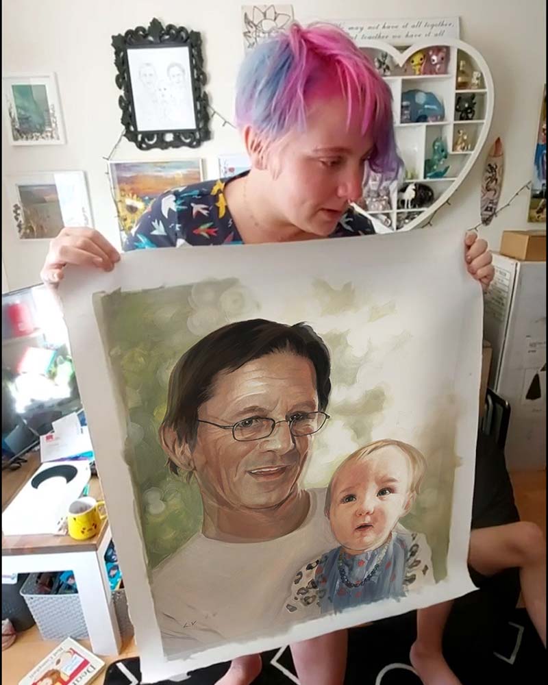 Woman holding a portrait of a man and baby.