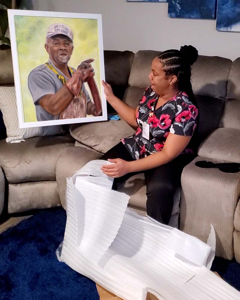 Woman holding a framed portrait of an older man.