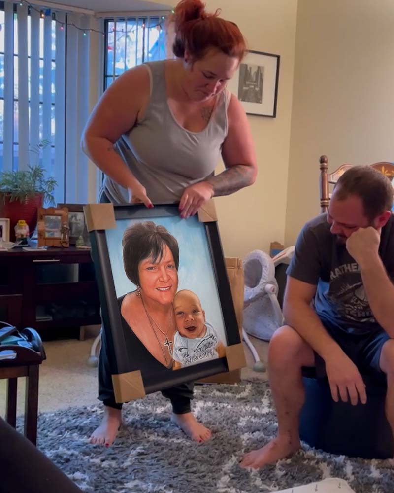 Woman and man unveil framed portrait of woman and baby.