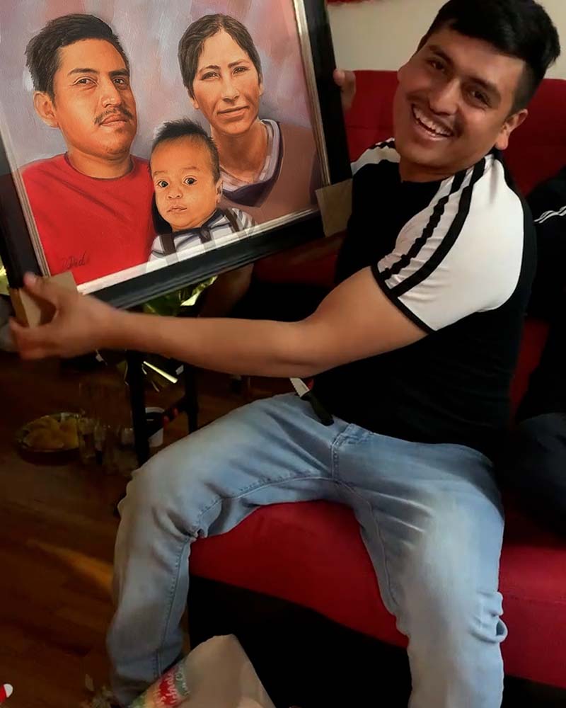 Smiling man holding framed portrait of family.