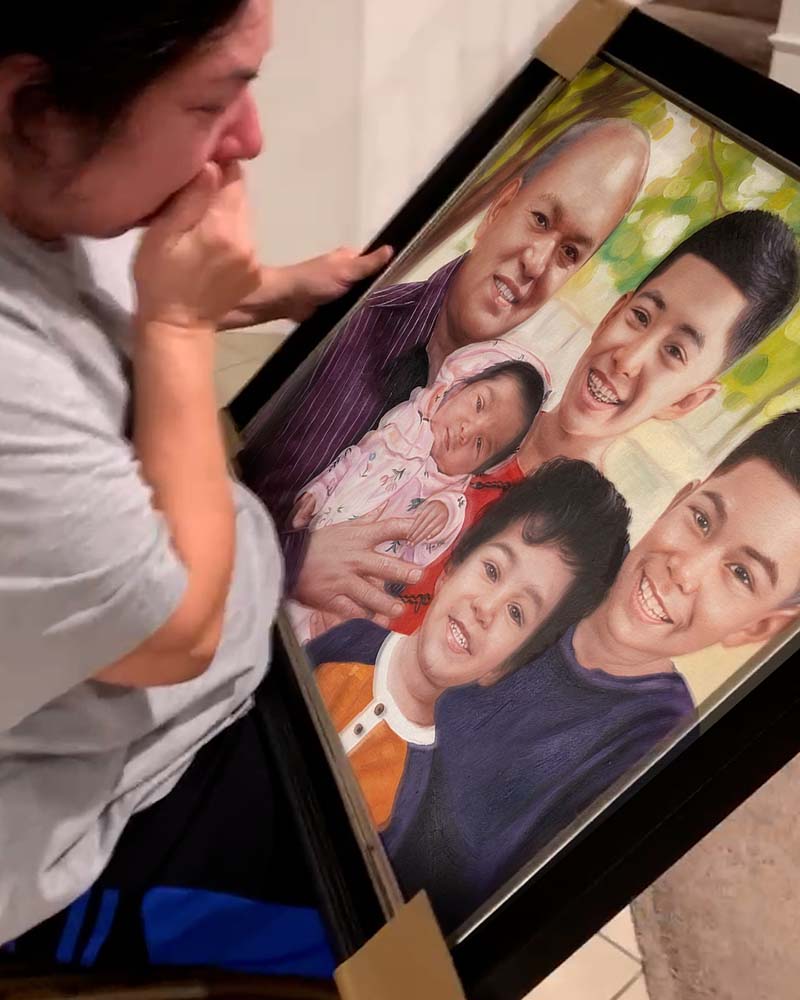 Woman crying while looking at a framed family portrait painting.