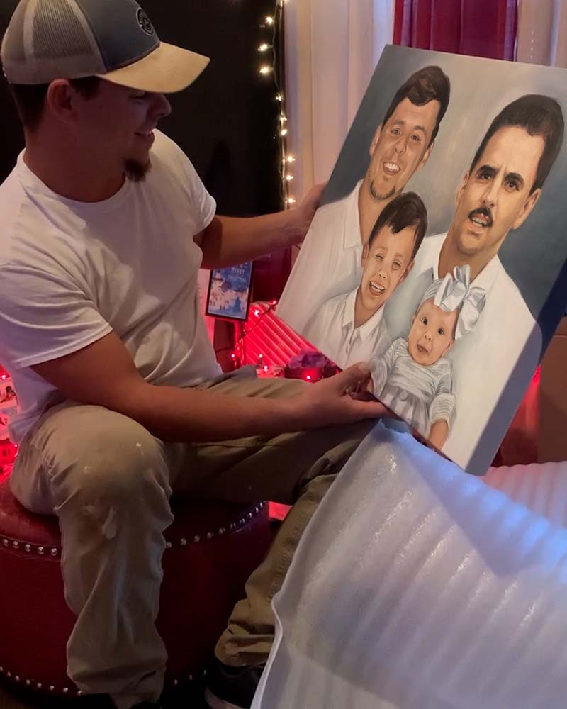 Man holding a painted portrait of a family.