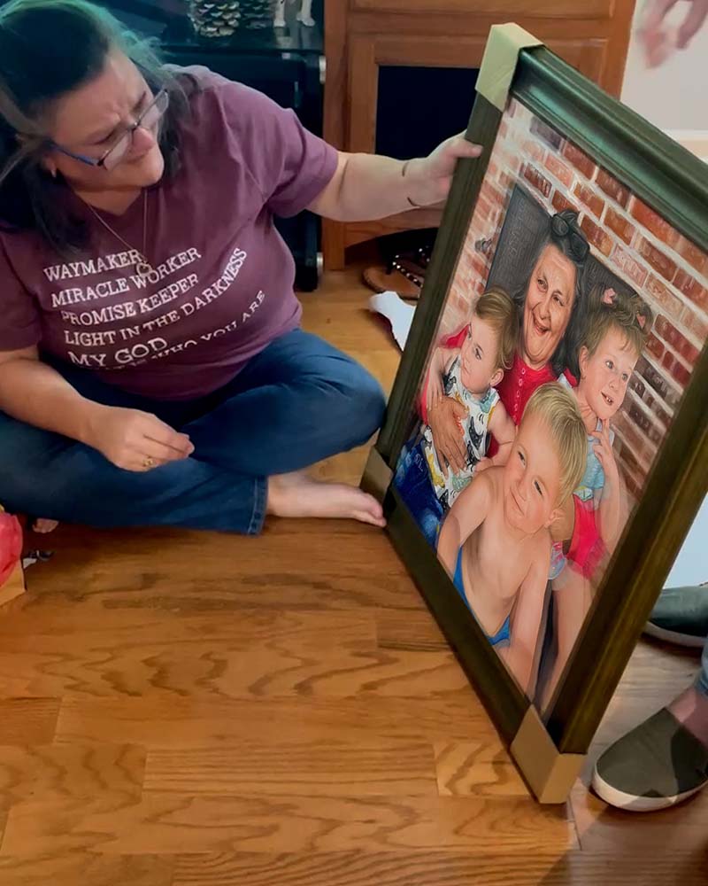 Woman examining framed portrait of grandmother with three grandchildren.