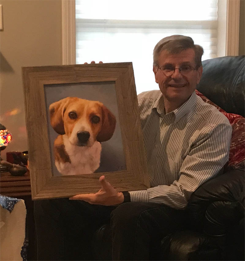 Man holding framed painting of beagle.
