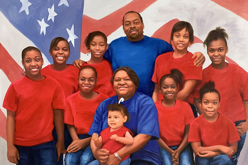 Large family portrait in front of an American flag, most wear red shirts.