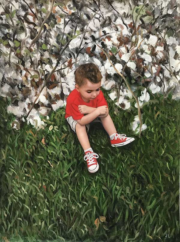 boy in a red shirt sitting in the grass against white cherry blossom tree