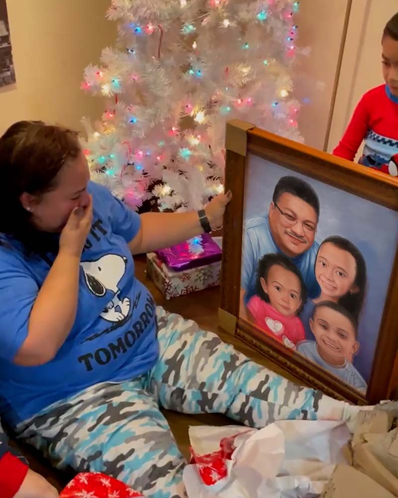 Woman crying while opening a framed family portrait in front of a Christmas tree.