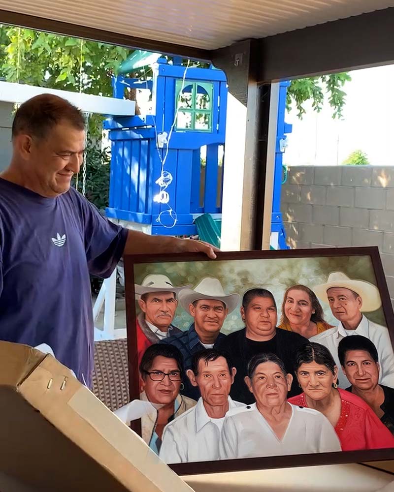 Man holding framed portrait of a large family group.