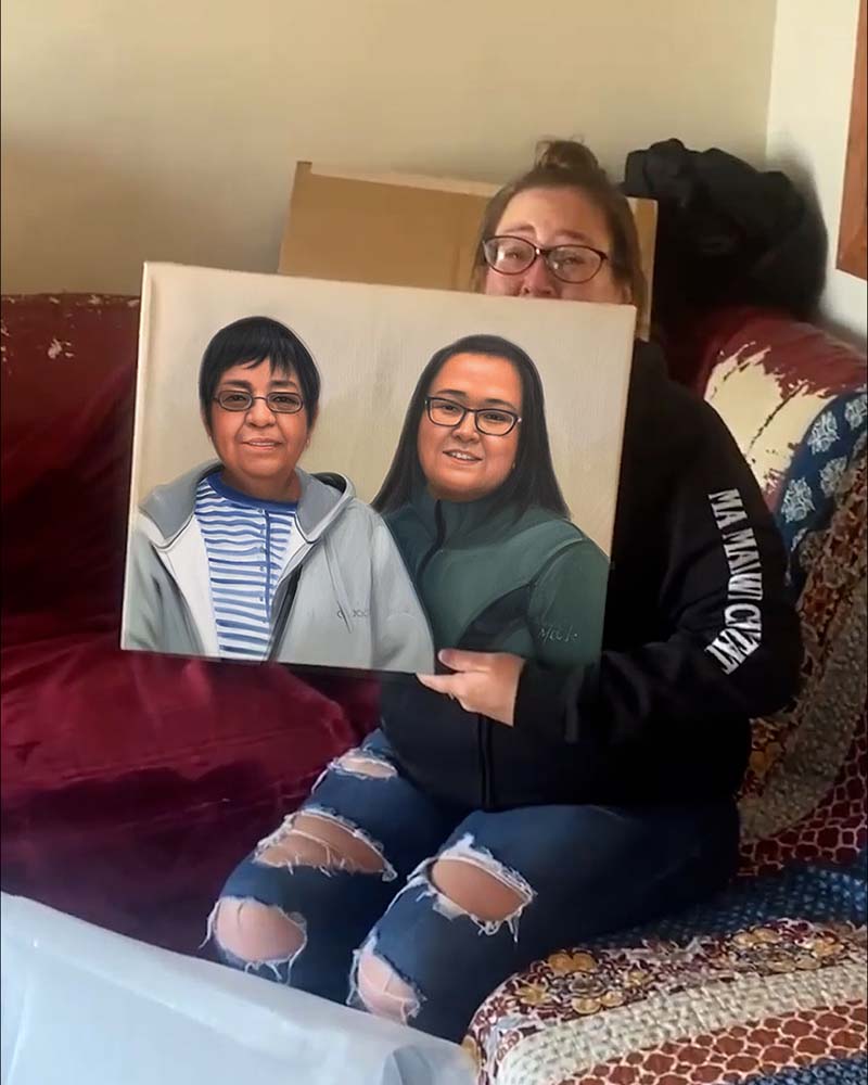 Woman holding a painted portrait of two women.