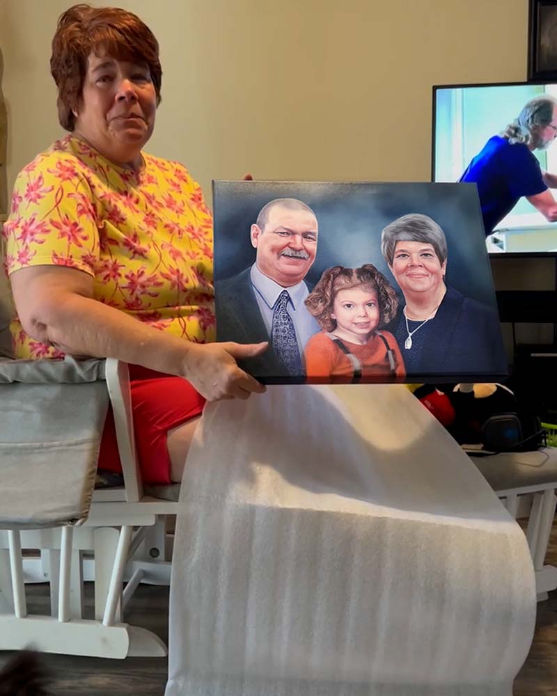 Woman holding a family portrait painting.