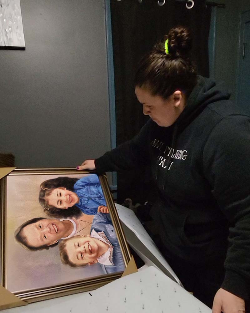 Woman unboxing a framed portrait of a grandmother and two grandchildren.