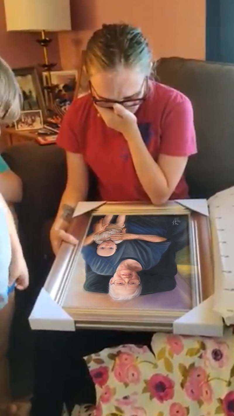 Woman crying while holding framed portrait of older woman holding baby.