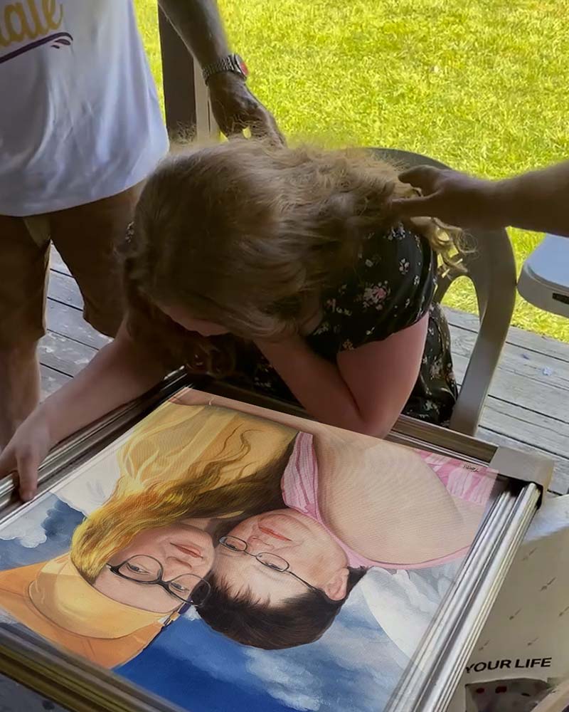 Woman emotionally viewing a framed portrait of two women.