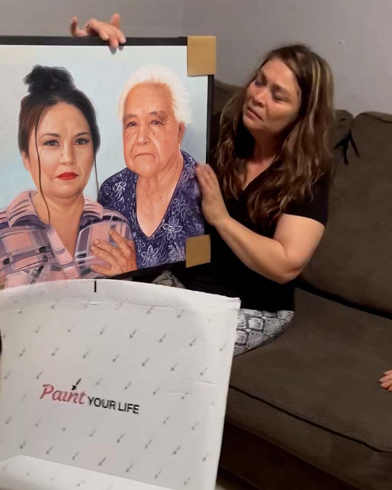Woman unveiling a painted portrait of two women.
