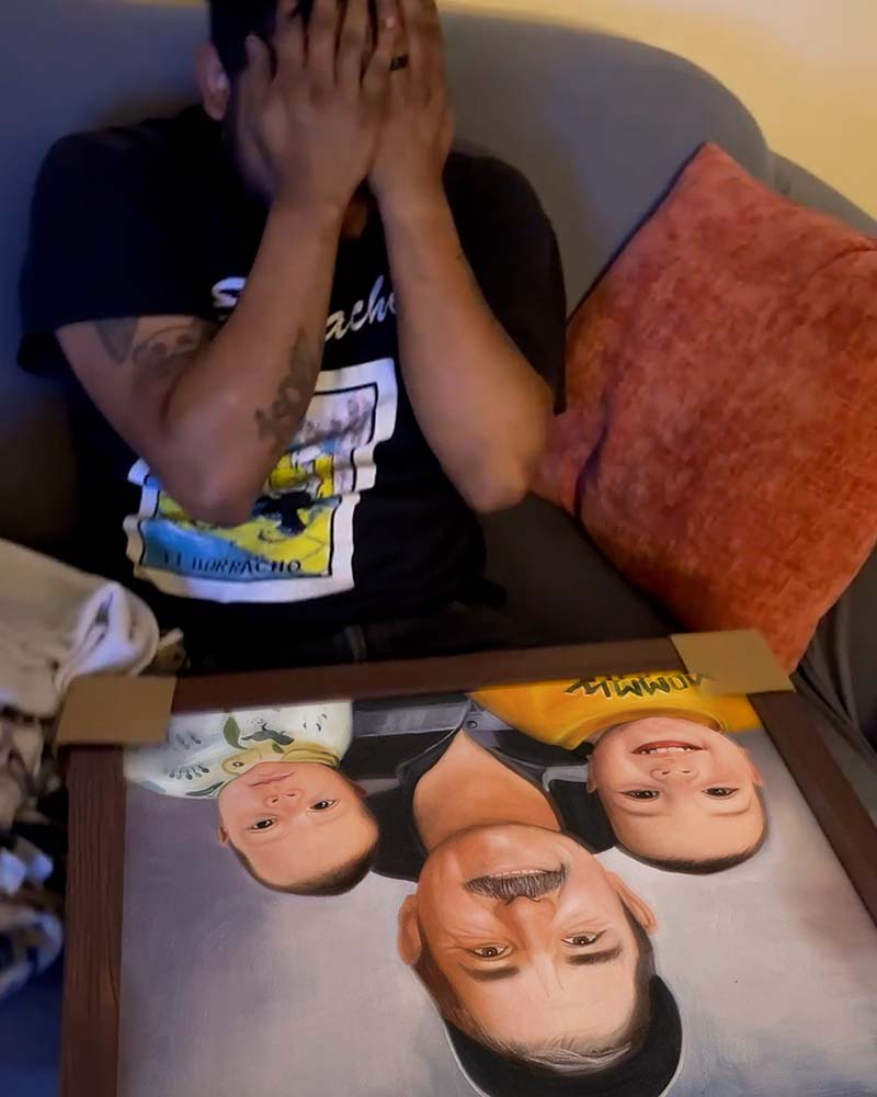 Man reacting emotionally to a framed portrait of a man and two young children.