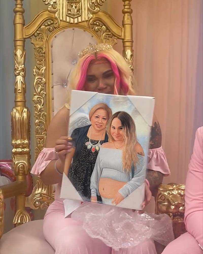 Woman in pink holding a painted portrait of two women, one pregnant.