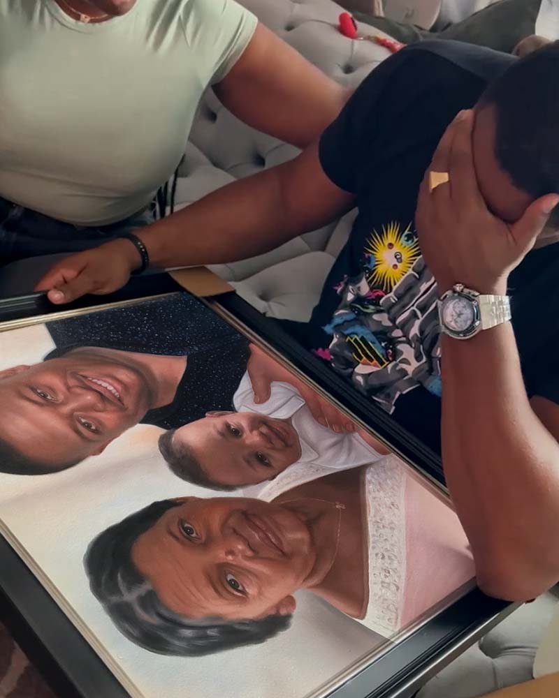 Framed portrait of a family: man, baby, and woman.  Two people looking at the portrait.