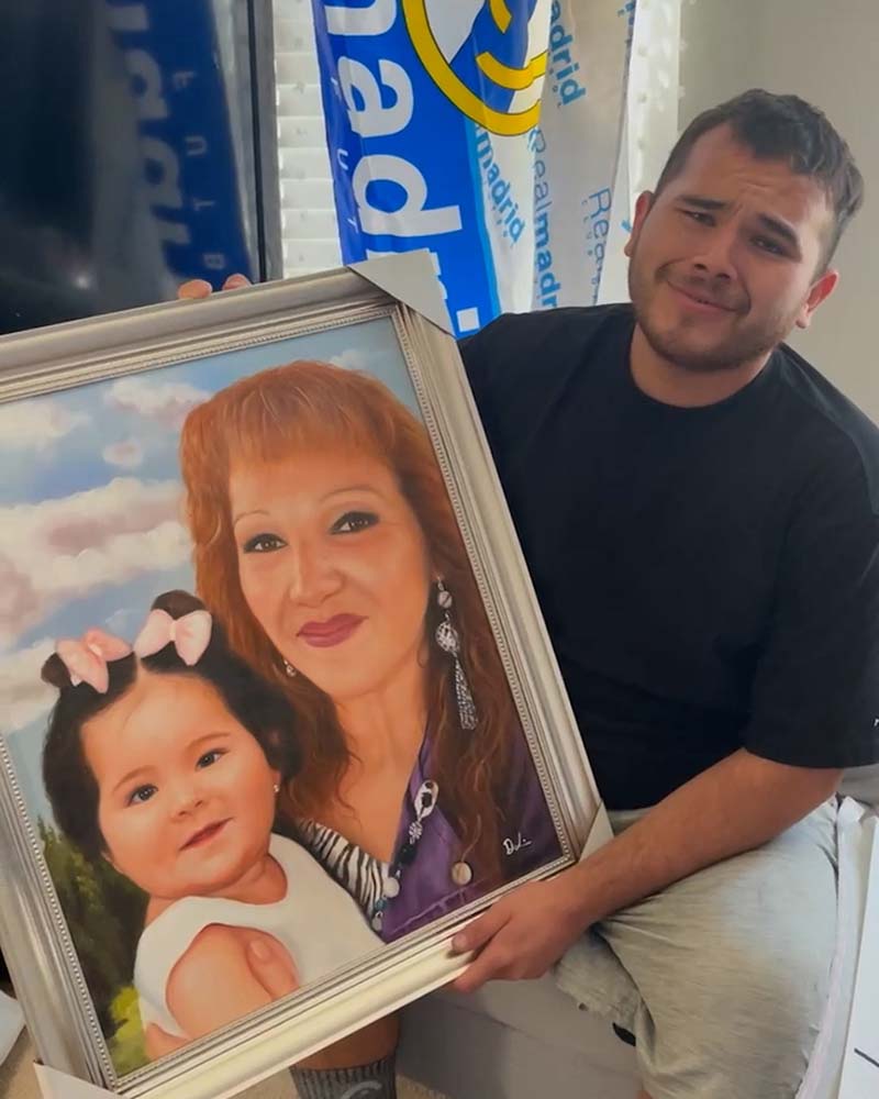 Framed portrait of a woman and young girl, held by a man.