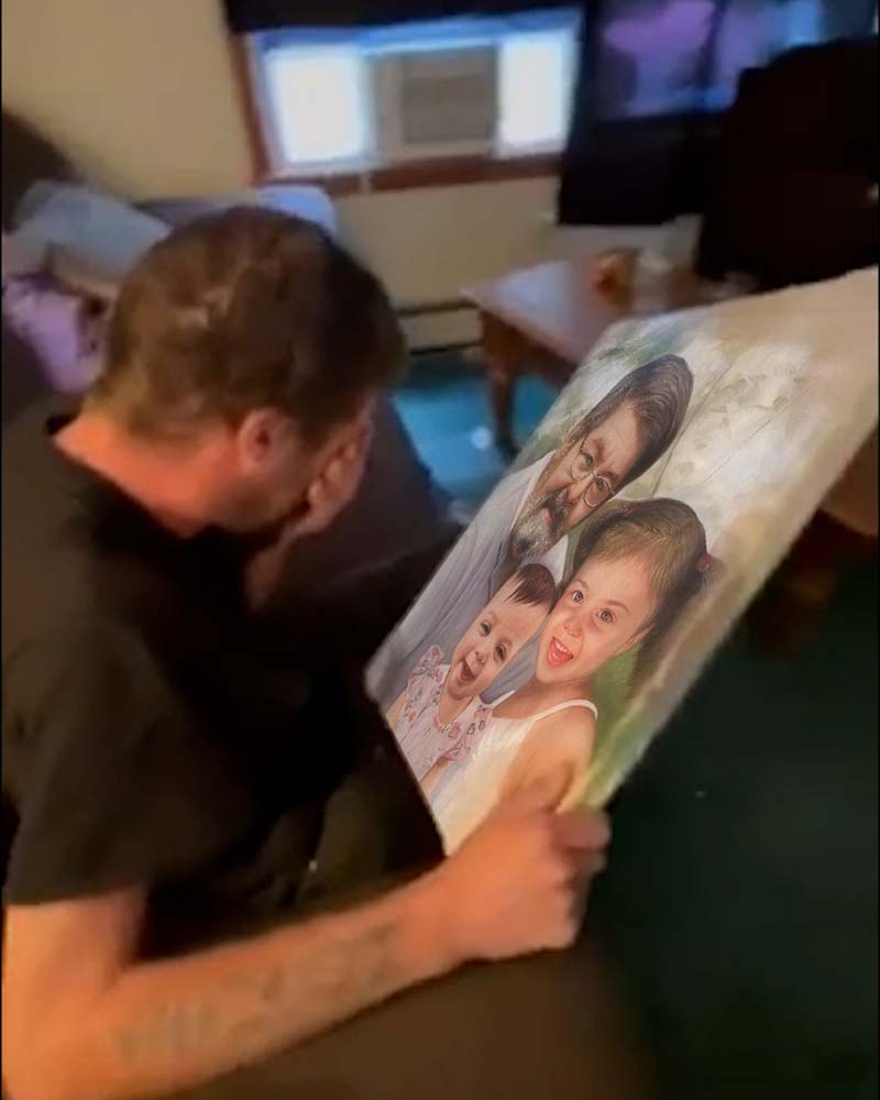 Man looking at a portrait of an older man and two young girls.