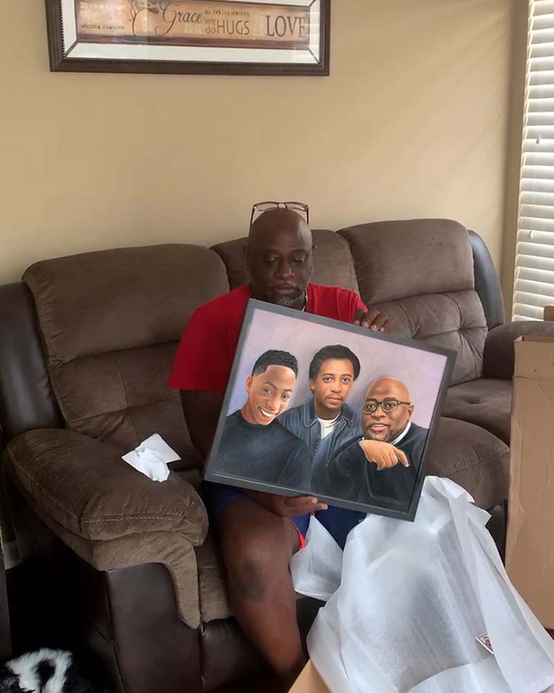 Man holding framed portrait of three men.
