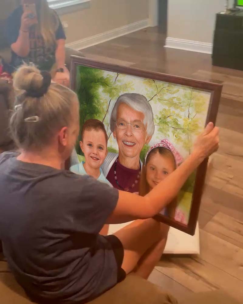 Woman unveiling a painted portrait of her grandmother and two young children.