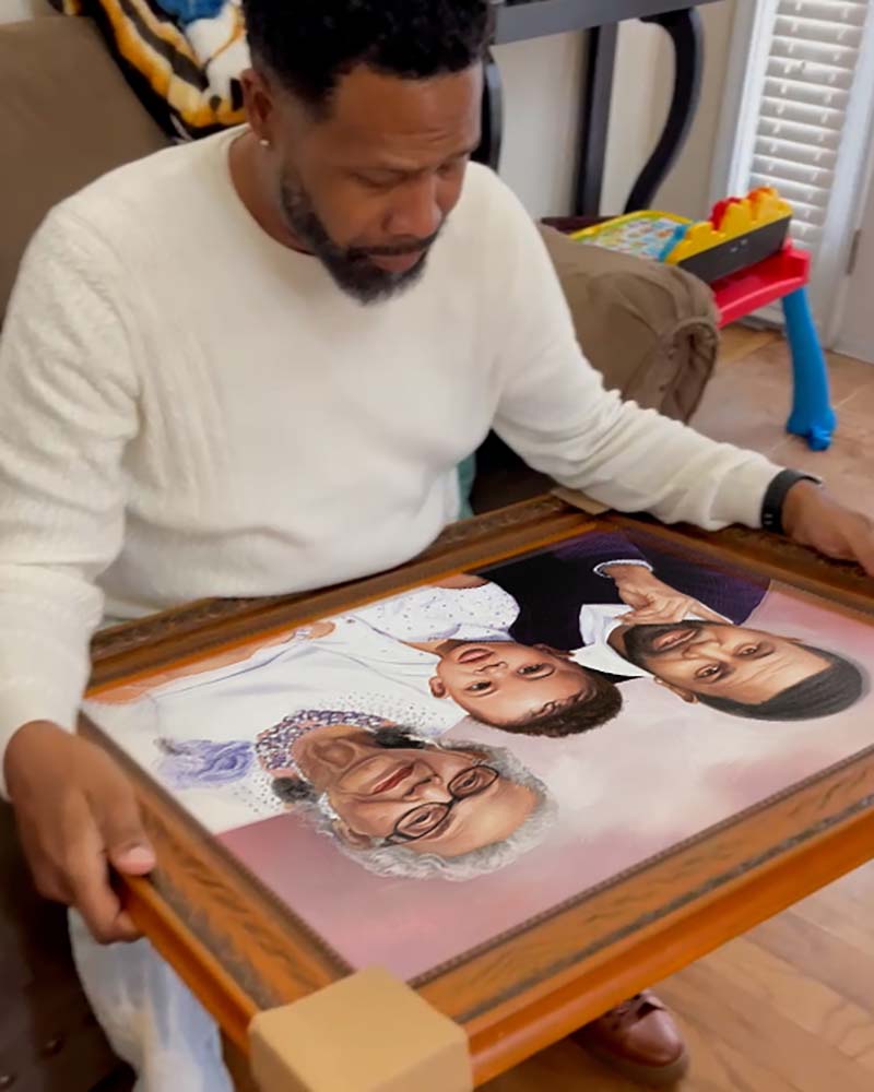 Man examining framed portrait of elderly woman, man, and child.