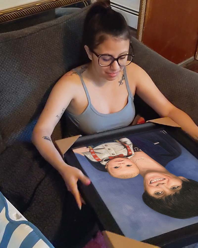 Woman in glasses unwrapping a framed portrait of a woman and baby.