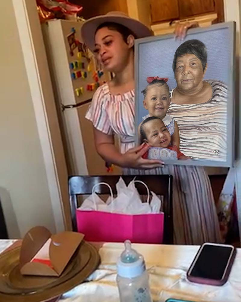 Woman holding framed portrait of older woman and two toddlers.