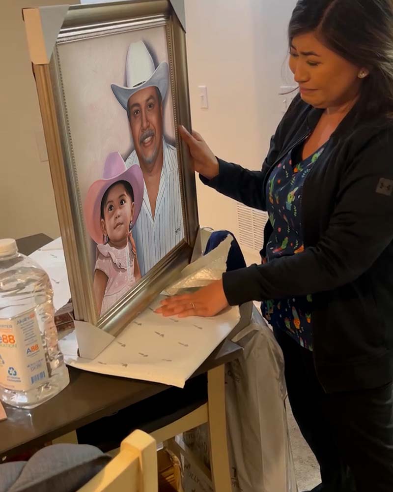 Woman unpacking framed portrait of a man and young girl in cowboy hats.