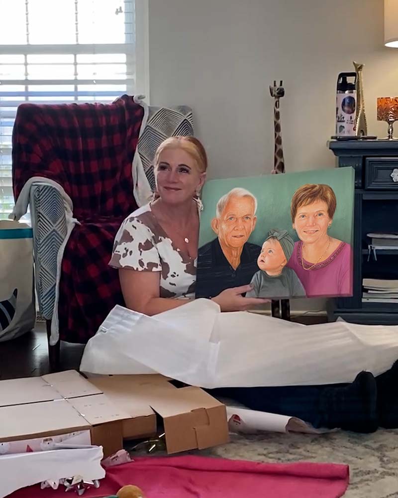 Woman holding a family portrait painting, surrounded by gift wrap and boxes.