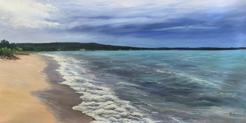 Beach scene with waves lapping the shore under a cloudy sky.