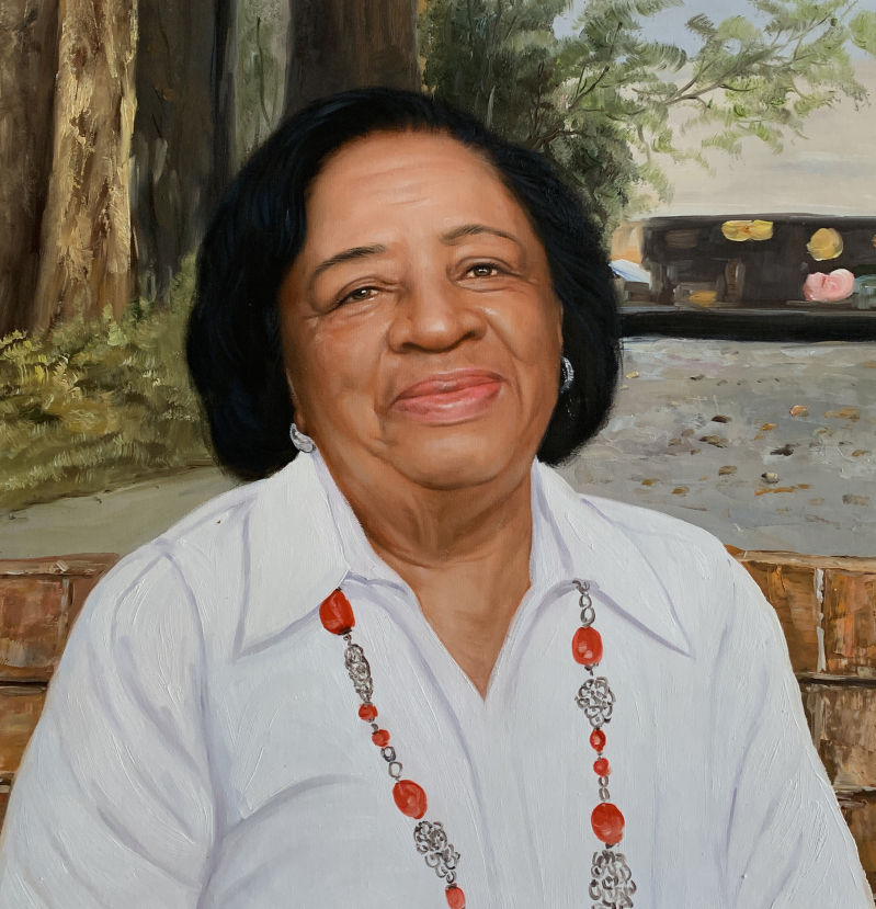 Portrait of a smiling Black woman wearing a white shirt and red necklace.