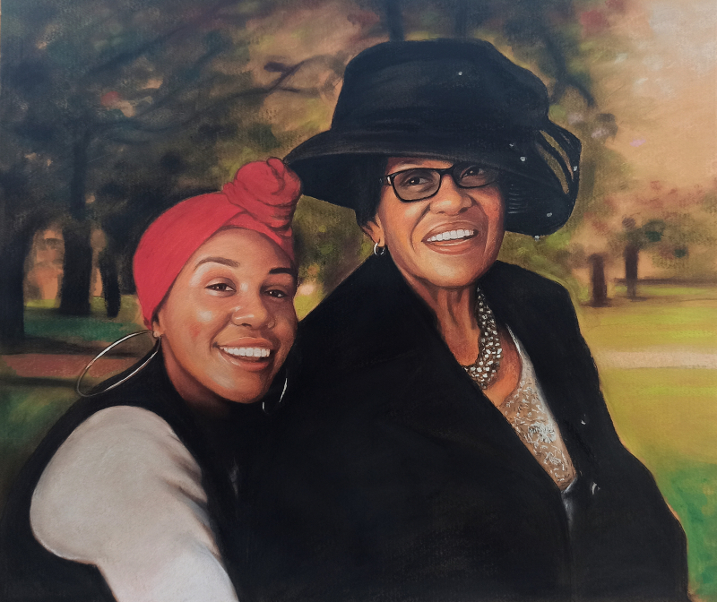 Portrait of two smiling Black women, one wearing a red head wrap and the other a black hat.