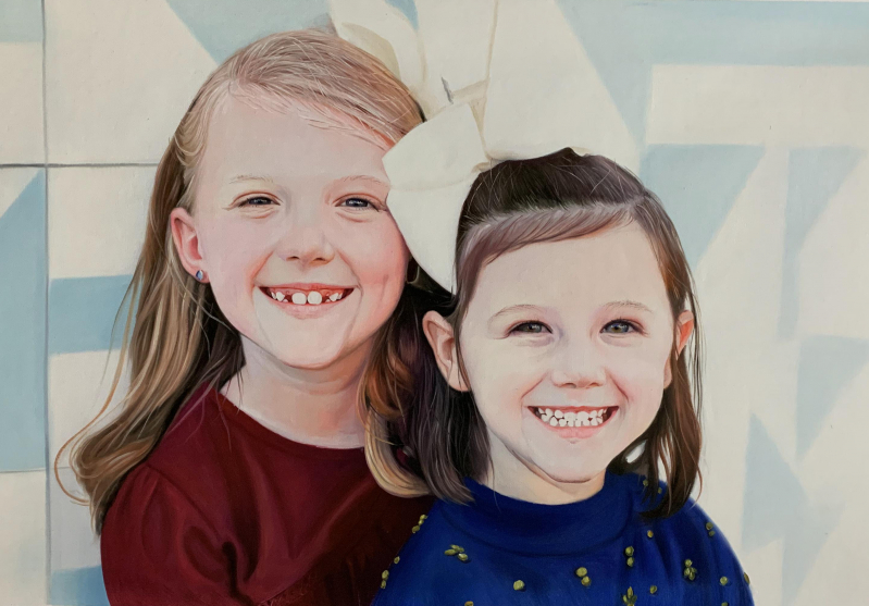 Portrait of two smiling girls, one with blonde hair and a burgundy shirt, the other with brown hair and a blue shirt.
