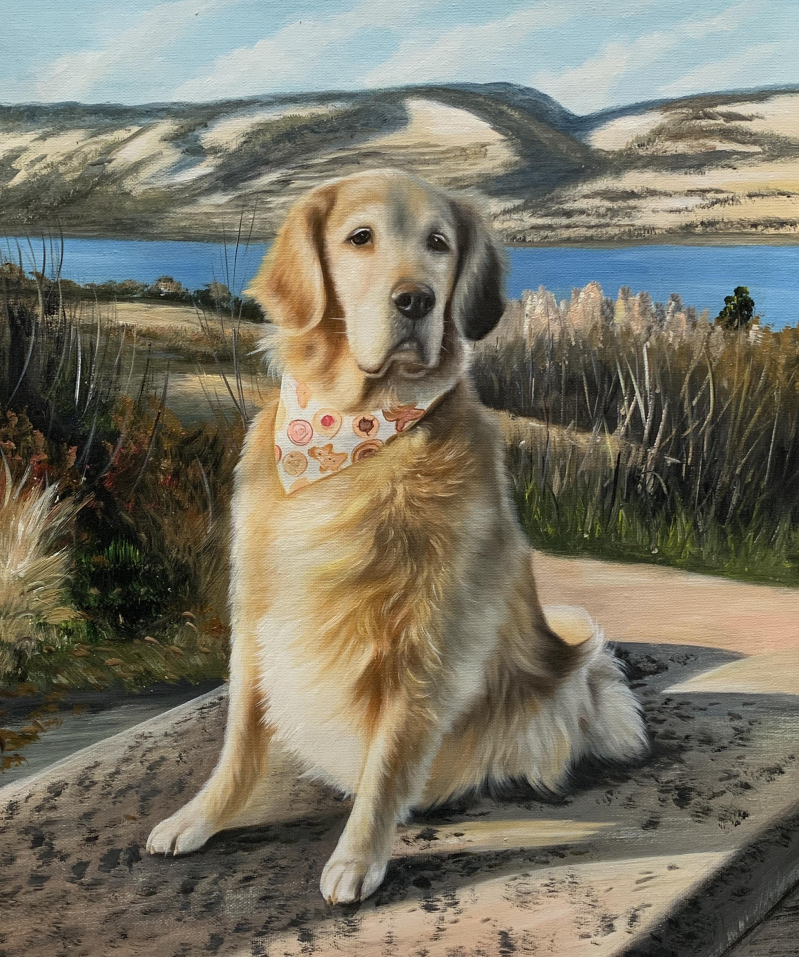 Golden Retriever portrait, wearing a bandana, sitting outdoors by a lake.