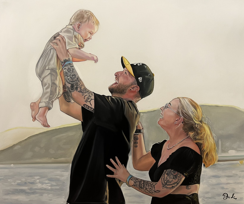 Portrait of a tattooed father lifting his baby in the air while laughing with his wife by the water.