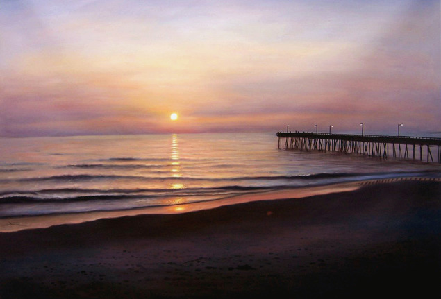 Sunset over ocean with pier and beach.