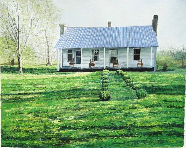 White farmhouse with blue metal roof and rocking chairs on porch, green lawn, and shrubs.